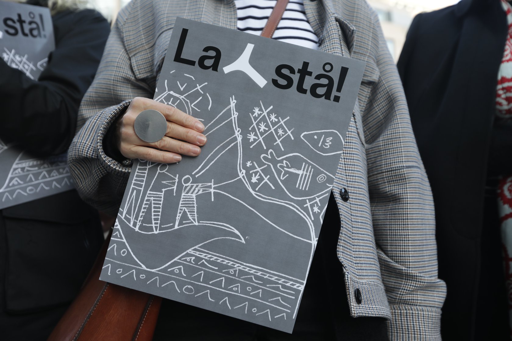 Foto av gavlveggen til Y-blokka med demonstranter med stripete genser foran. I front, Henie Onstad kunstsenters direktør Tone Hansen. Alle med hendene i været (Y-form)