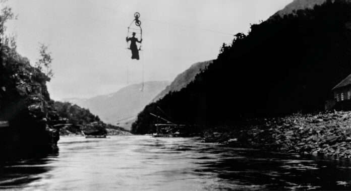 Historisk bilde av kvinne i en taubane over en fjord